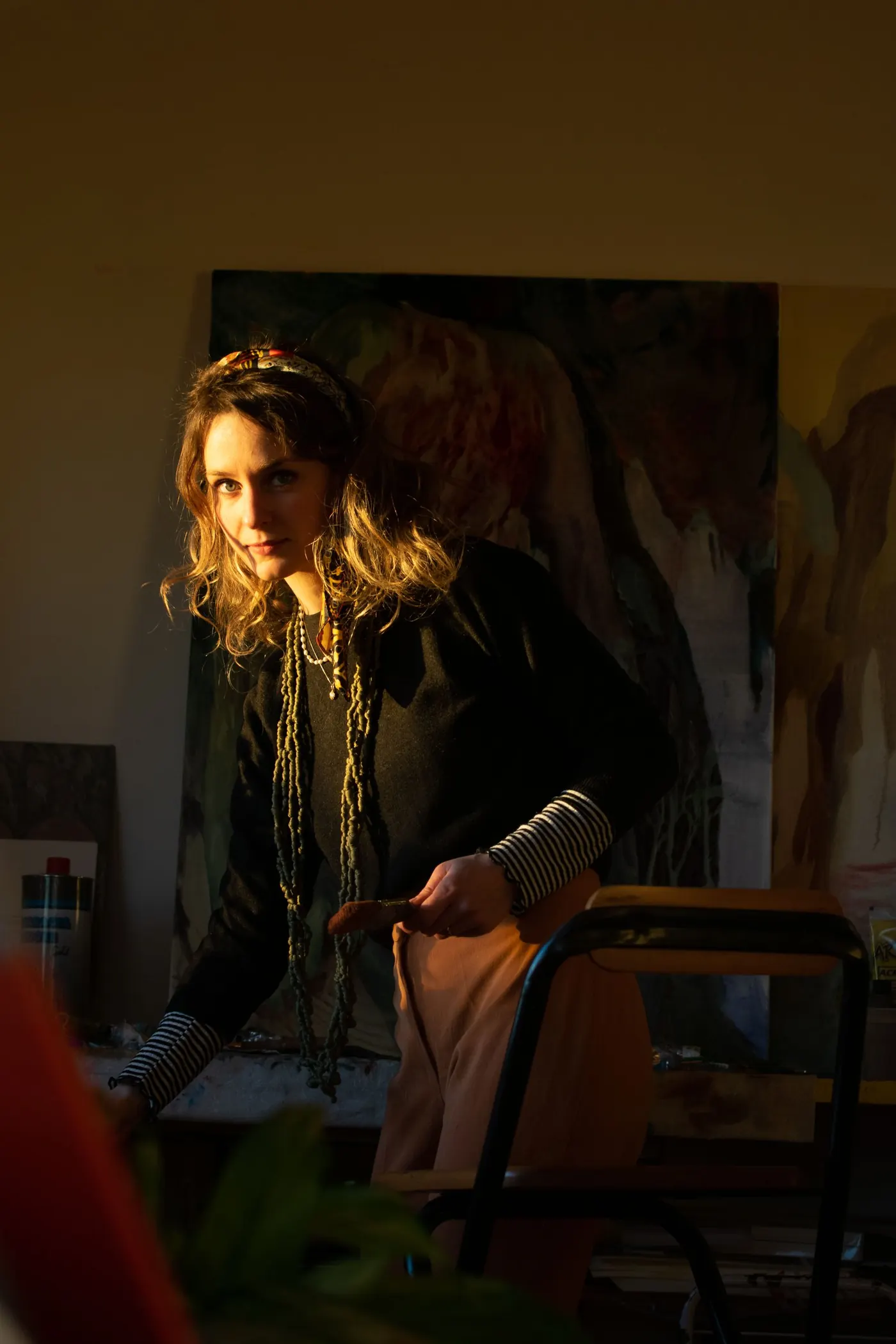 Artist working in a warm, shadowy painting studio